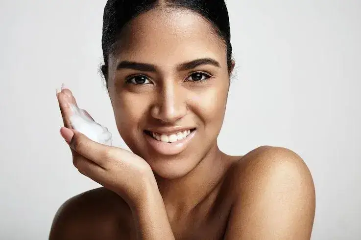 Cleansing skin concept smiling woman with a foam on a hand